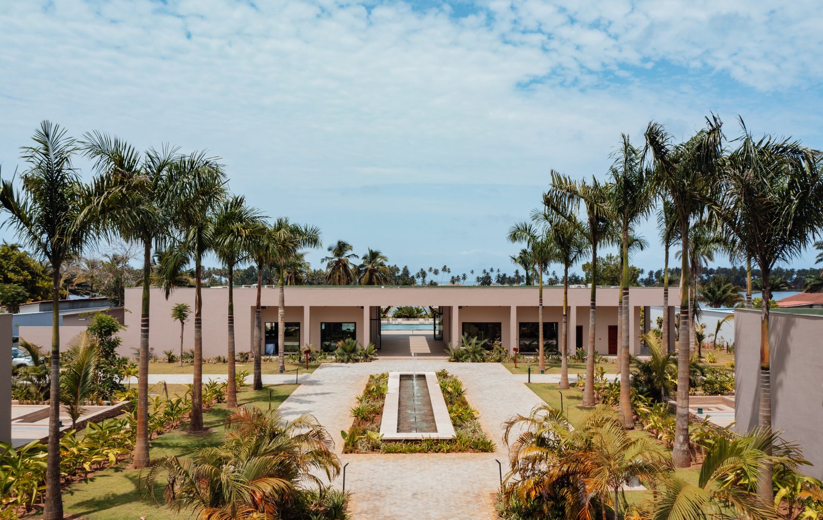 View of the hotel with palm trees and a central walkway